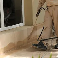 General pest control technician spraying exterior perimeter around a home in Houston, TX