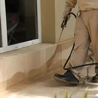 General pest control technician spraying exterior perimeter around a home in Houston, TX