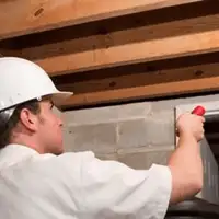 Termite inspection technician checking a basement wall and framing for termite activity in Houston, TX